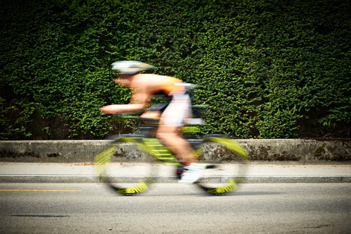 Triathlet auf dem Rad vor einer Hecke