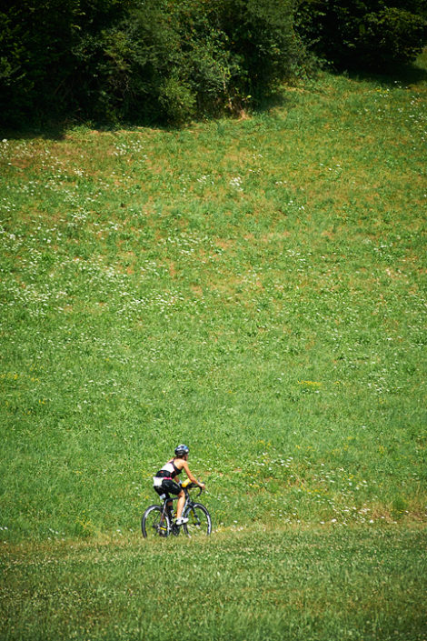 Eine Triathletin auf dem Rad vor einer Wiese