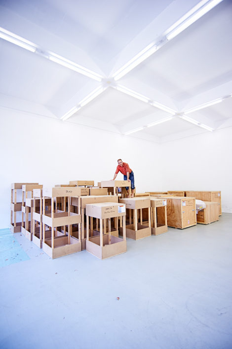 Portrait von Roman Räss auf Holzkisten in einer Galerie