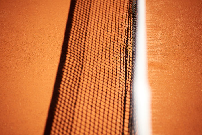 Der Schatten vom Tennisnetz auf dem Sandplatz