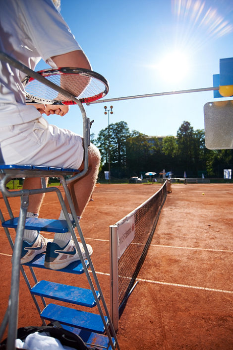 Der Trainer sitzt auf dem Schiedsrichterstuhl in der Sonne