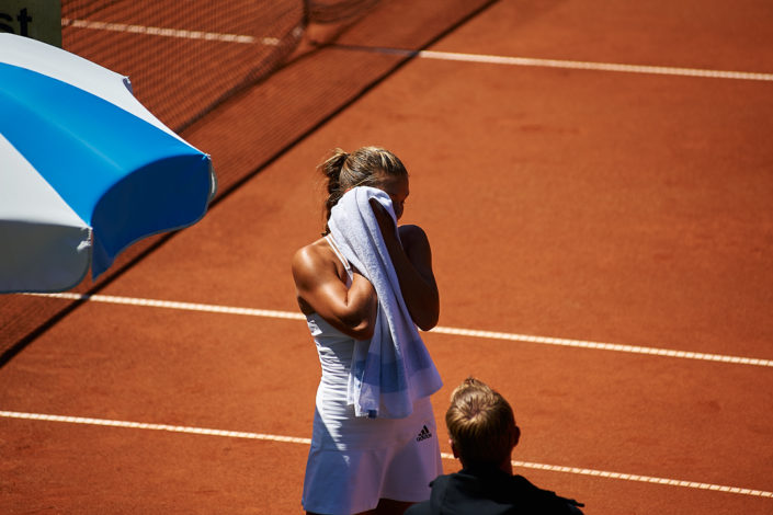 Eine Tennisspielerin trocknet ihr Gesicht mit einem Tuch