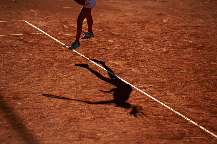 Schatten einer Tennisspielerin beim Aufschlag