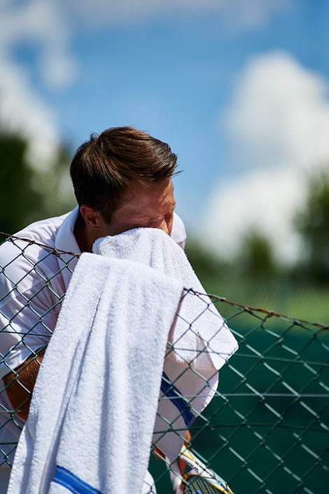 Ein Tennisspieler trocknet sein Gesicht mit einem Tuch