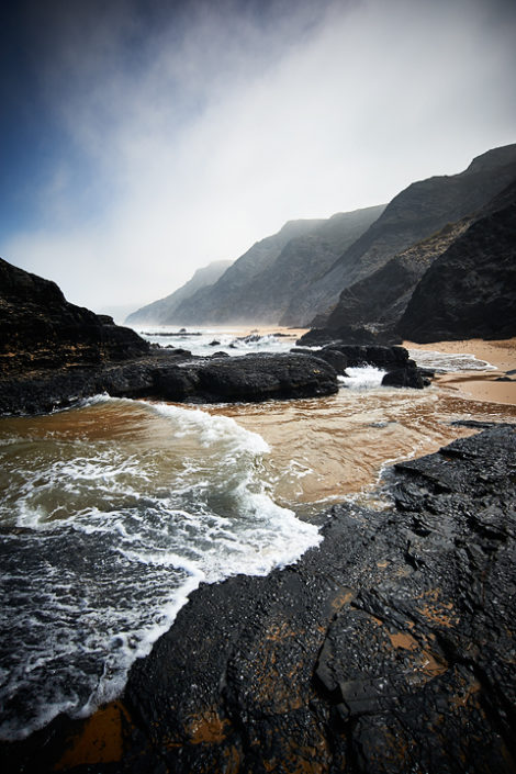 Blick vom Strand der dunstigen Felsenküste entlang