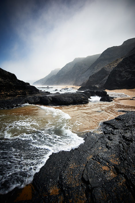 Blick vom Strand der dunstigen Felsenküste entlang