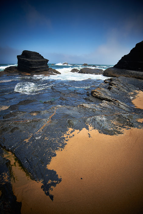 Das Wasser fliesst über den flachen Felsenstrand