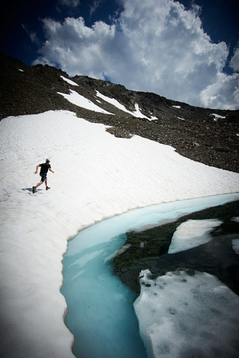 Ein Mann rennt entlang eines mit Eisschollen bedeckten Bergsees