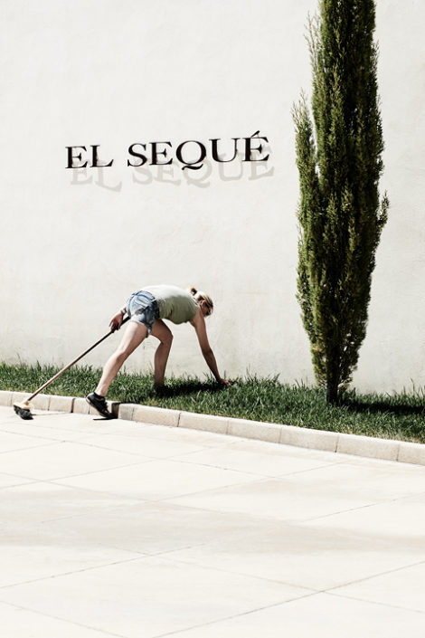 Eine Mitarbeiterin reinigt den Rasen vor der Fassade der Bodegas y Viñedos el Sequé