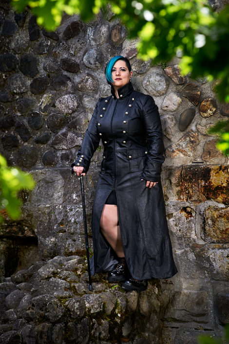 Eine Frau im Gothiclook steht vor einer Schlossmauer