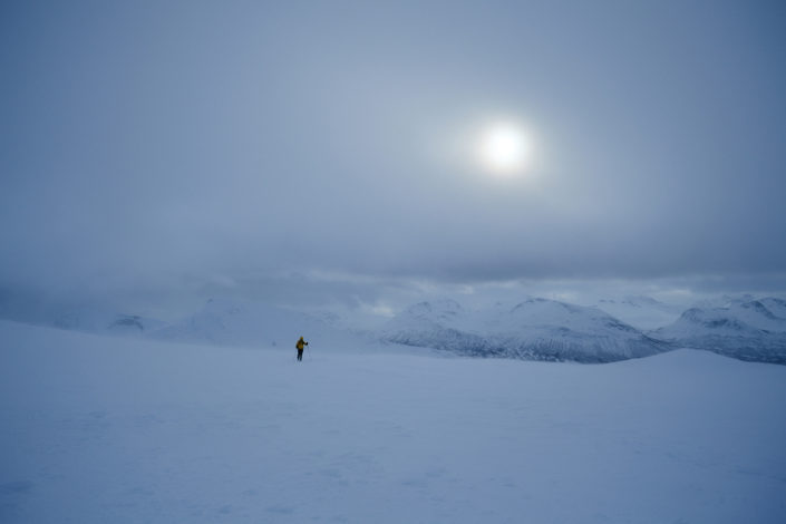 Ein Skitourengänger erreicht den Gipfel im Schneesturm