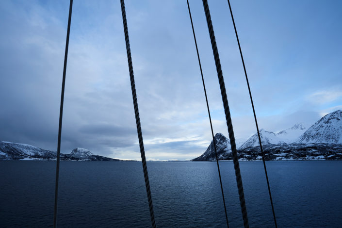 Blick vom Mast in grosser Höhe auf den Fjordeinschnitt mit Seilen im Vordergrund