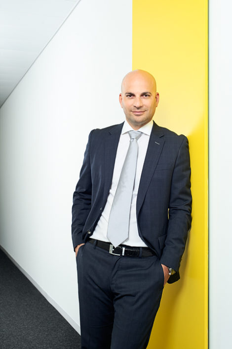 Portrait eines Managers im Anzug vor Wand mit gelbem Streifen
