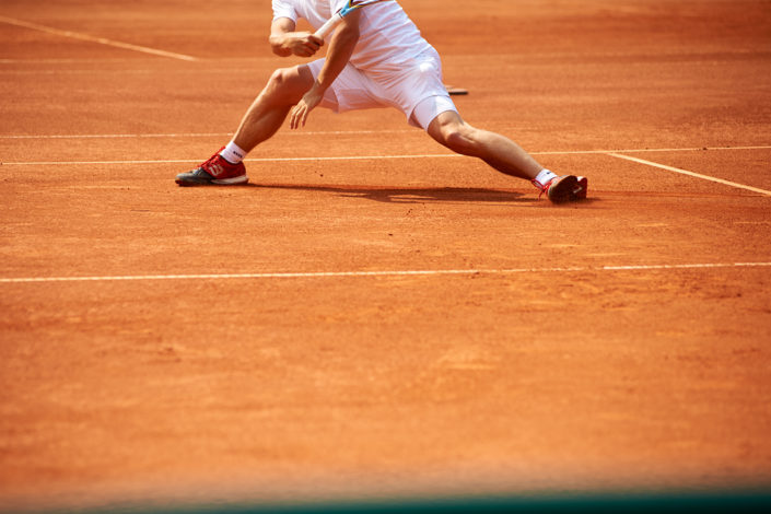 Ein Spieler schleift auf dem Sandplatz