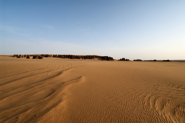 Felszapfen ragen in der Ferne aus dem Wüstensand empor