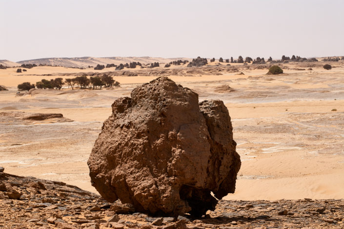 Eine Felskugel steht auf dem steinigen Wüstenboden