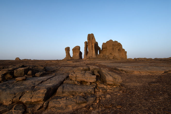 Imposante Felssäulen ragen in der Ferne aus dem steinigen Wüstenboden empor