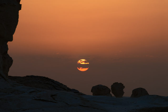 Die glühende Morgensonne leicht verdeckt durch kleine Wolken