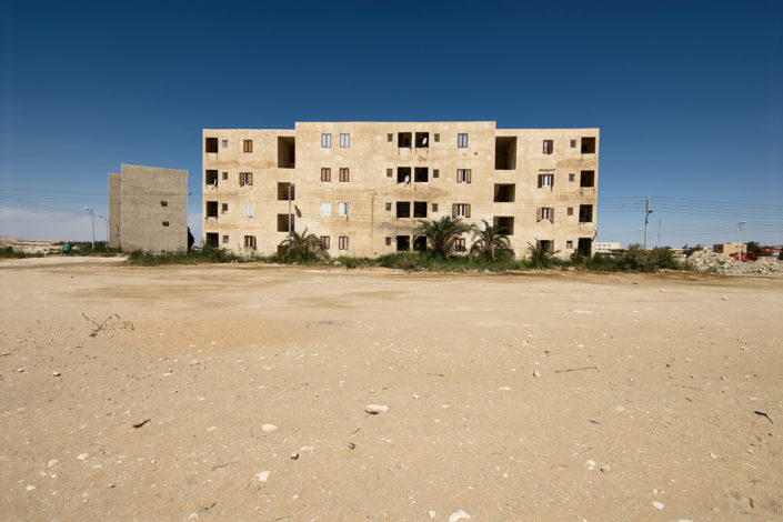 Einfaches Wohngebäude am Rande eines Sandplatzes