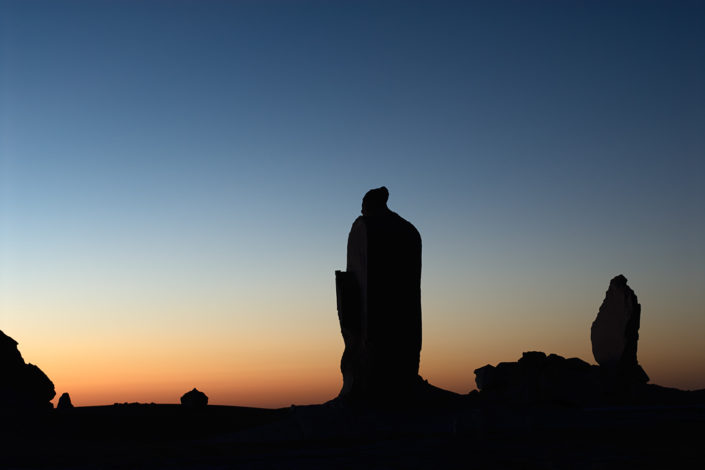 Das erste Morgenlicht lässt eine Felssäule als Silhouette erscheinen