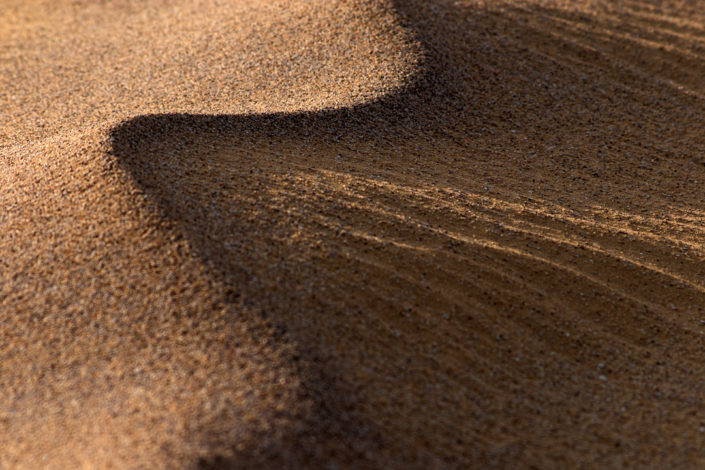 Die ersten Sonnenstrahlen erfassen den welligen Wüstensand