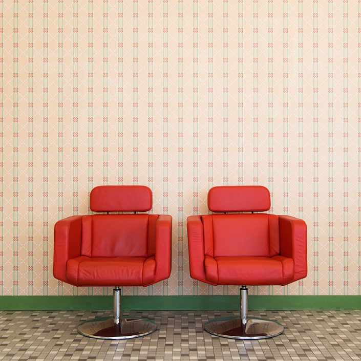 Zwei rote Sessel vor einer Tapete